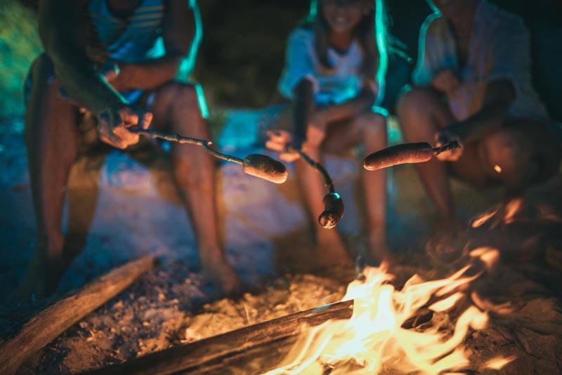 family cooking on a stick with campfire
